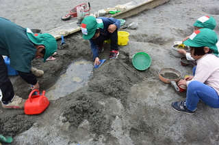 ４歳児が砂場で山を作って水を流しています