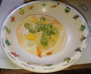餃子の皮で作られた枝豆の緑とコーンの黄色がきれいなピザ