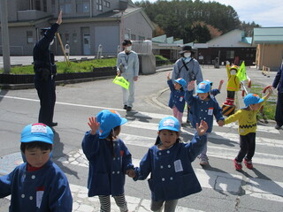 年少さんが手を挙げて横断歩道をわたっています