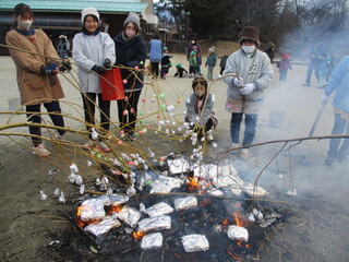 保育士が園庭で繭玉を焼いています