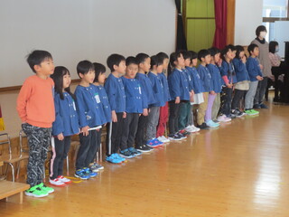 ステージの前で子どもたちが立って歌っています。