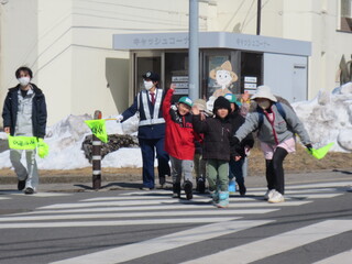 子どもが手を挙げて横断歩道を渡っています。