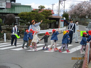 子どもが保育士と横断歩道を渡っています