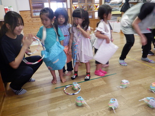 ２歳児が夏祭りごっこで輪投げを楽しんでいます。