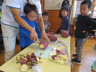 さつまいもを保育士と一緒に切っています。