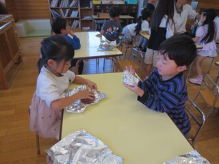 さつまいもをアルミホイルに包んでいます。