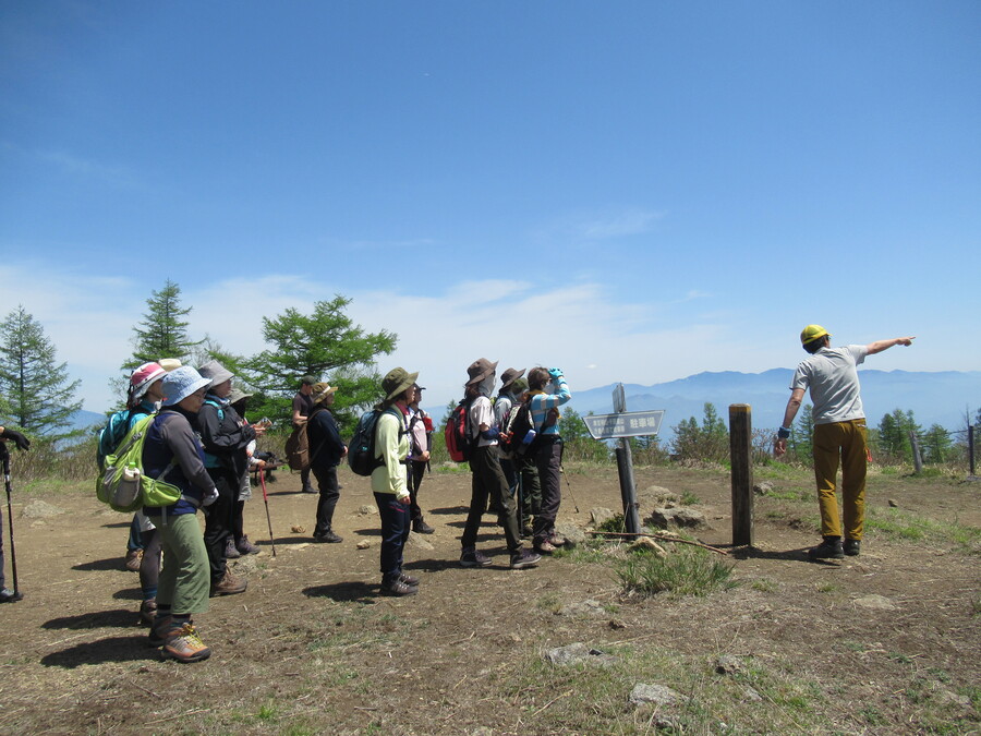 山頂から遠くに見える山々をガイドの石川さんが解説しています